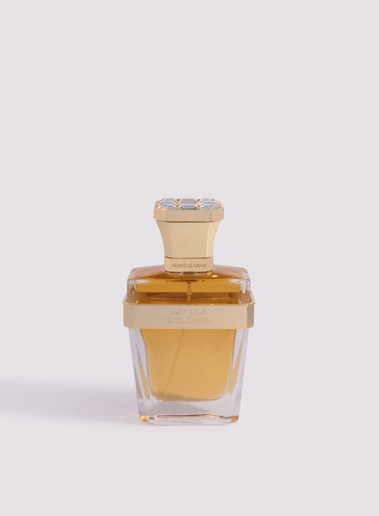 A clear glass bottle with a gold cap and band, filled with amber-hued Oud Zayed Parfum by Hind Al Oud, an exquisite Emirati fragrance, showcased against a light pale background.