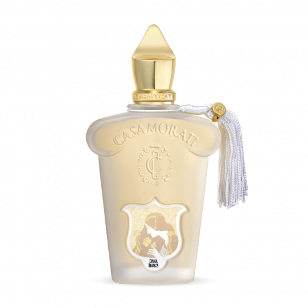 A white and gold XERJOFF Casamorati 1888 Dama Bianca Eau de Parfum bottle features a gold cap, ornate crest, white tassel, and base silhouette, reflecting its floral woody musk scent.