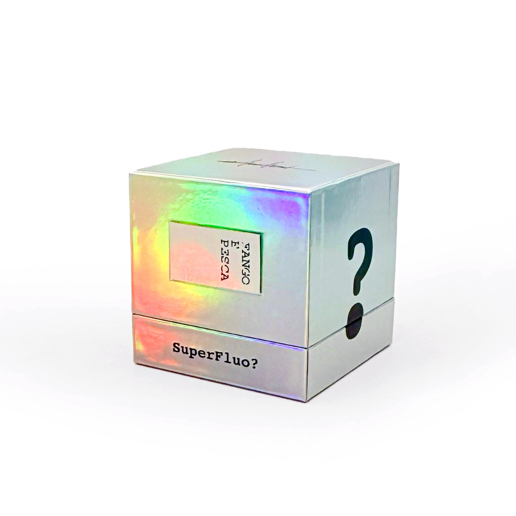 A holographic cube box with a question mark and "SuperFluo?" hints at Filippo Sorcinelli’s SUPERFLUO FANGO E PESCA "Mud and Fishing" Eau de Parfum. The label reads TANSO P.BSA, with "FANGO E PESCA" on the front, set against a white background.