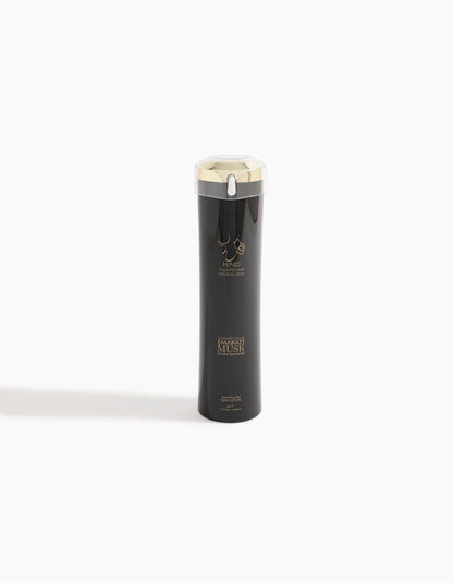A tall, sleek black bottle with a silver cap and gold accents, featuring the logo and text Emarati Musk Body Lotion and Hind Al Oud on the front, evokes the luxurious allure of musk, standing upright against a plain white background.