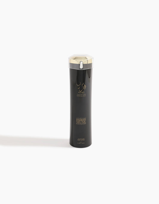 A tall, sleek black bottle with a silver cap and gold accents, featuring the logo and text Emarati Musk Body Lotion and Hind Al Oud on the front, evokes the luxurious allure of musk, standing upright against a plain white background.