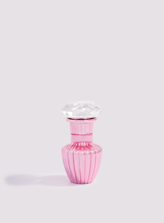 The Pink Petite Concentrated Oil 3ml by Hind Al Oud features a small pink ribbed bottle with a large, faceted gem cap, evoking the elegance of jasmine and cashmere wood against a plain light background.