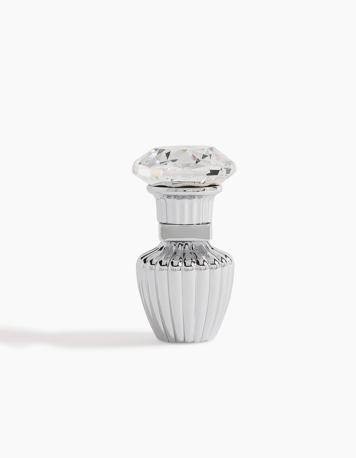 A small, elegant silver Sheikh A Petite Concentrated Oil 3ml bottle by Hind Al Oud, with vertical ridges and a diamond-shaped clear cap, radiates luxury against a white background.