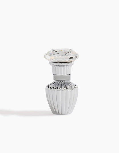 A small, elegant silver Sheikh A Petite Concentrated Oil 3ml bottle by Hind Al Oud, with vertical ridges and a diamond-shaped clear cap, radiates luxury against a white background.