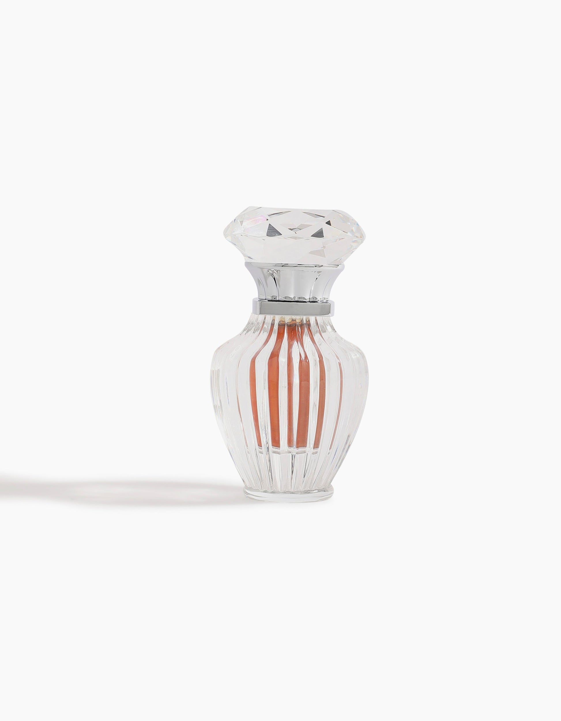 A clear, faceted glass bottle with a diamond-shaped lid holds Sheikh A Jewel Concentrated Oil 6ml by Hind Al Oud, featuring a peach-colored liquid and displayed against a white background.