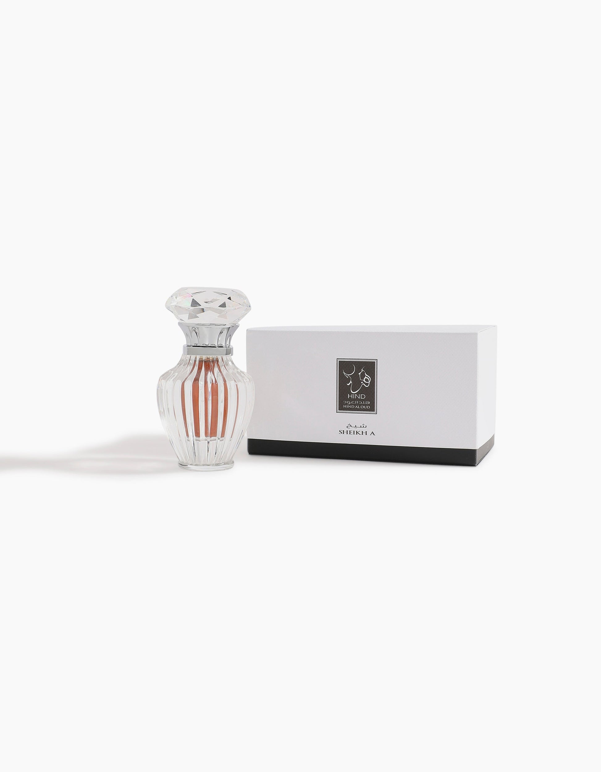A clear, faceted 6ml Sheikh A Jewel Concentrated Oil bottle by Hind Al Oud with light amber liquid stands next to a white rectangular box featuring a dark label and black base, both displayed against a white background.