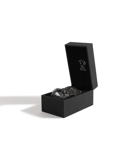 A black rectangular box with the lid open reveals a clear glass bottle of Sheikh A Jewel Concentrated Oil 6ml by Hind Al Oud. Inside the lid is a simple white graphic and brand text. The box casts a shadow on a white surface.