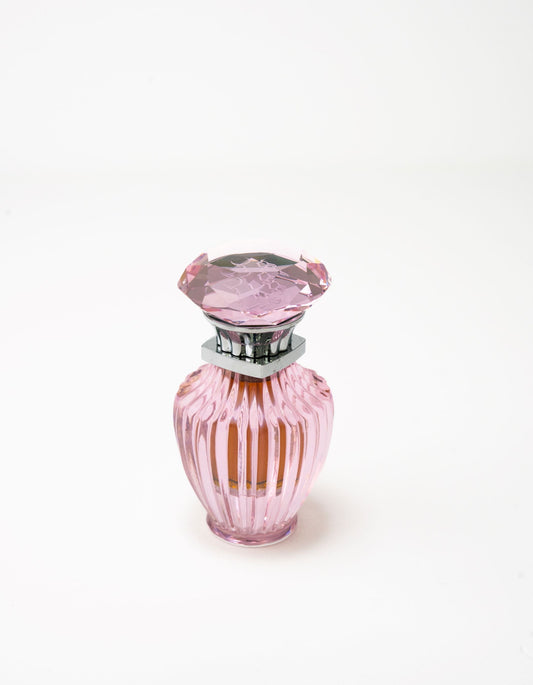 A 6ml Pink Oud Concentrated Oil by Hind Al Oud, in a pink ribbed glass bottle with a faceted stopper and silver neck, filled with amber Jasmine-infused liquid, set against a plain white background.