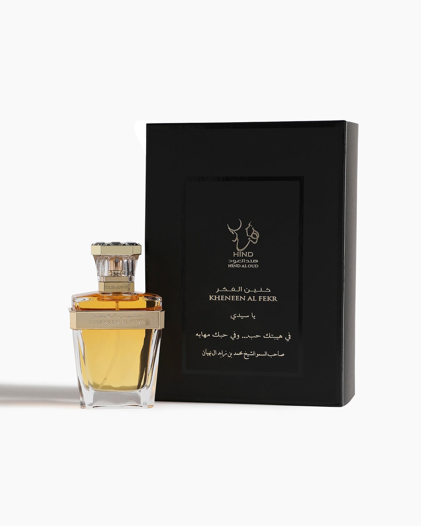 A clear glass bottle of Kheneen Al Fekr Parfum by Hind Al Oud, with gold accents and scents of cherry blossom and agarwood, stands beside a black box labeled KHENEEN AL FEKR in English and Arabic, on a white background.