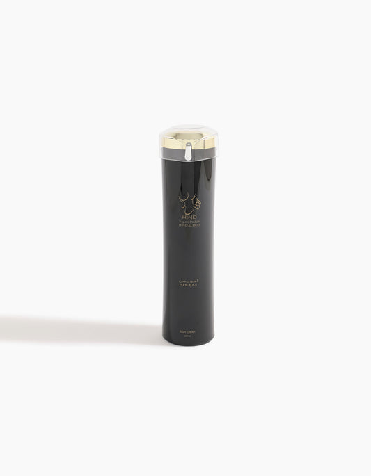 A sleek black bottle with a gold cap and minimalist gold design stands on a white background. Labeled Hind Al Oud and Ahojas Body Lotion, this product hints at notes of fig and tobacco for a luxurious skincare experience.