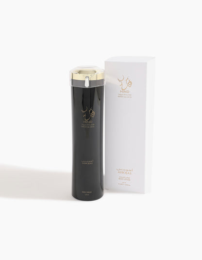 A black and gold bottle labeled Hind Al Oud’s Ahojas Body Lotion stands beside a white box with gold text and Arabic script, highlighting this luxurious lotion with fig notes on a plain white background.