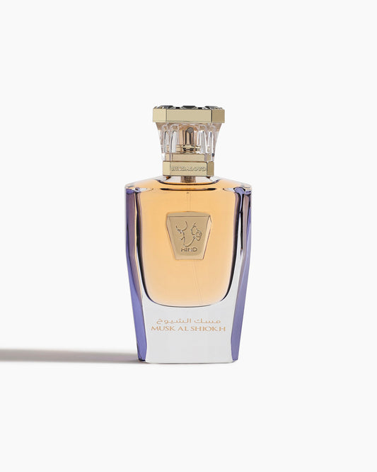 A luxury Musk Al Shiokh Parfum - Hind Al Oud bottle by Hind Al Oud, features gold accents, an ornate clear cap, and Arabic script, reflecting Emarati opulence against a white background.