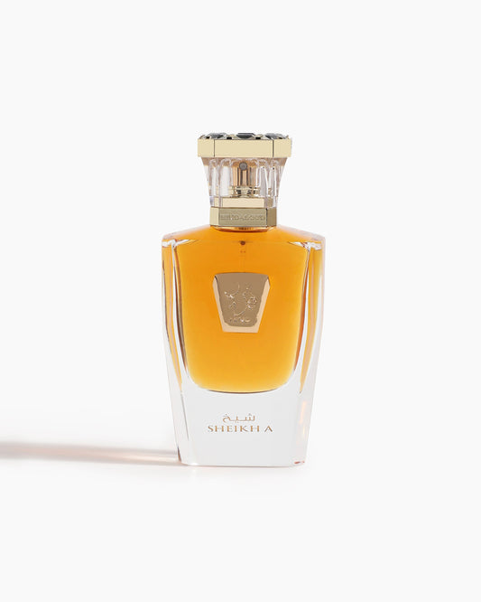 A clear glass Sheikh A Parfum bottle by Hind Al Oud features golden liquid, a gold and silver ornate cap, and a gold label. "Sheikh A" is printed in English and Arabic near the base, embodying Hind Al Oud’s signature elegance.