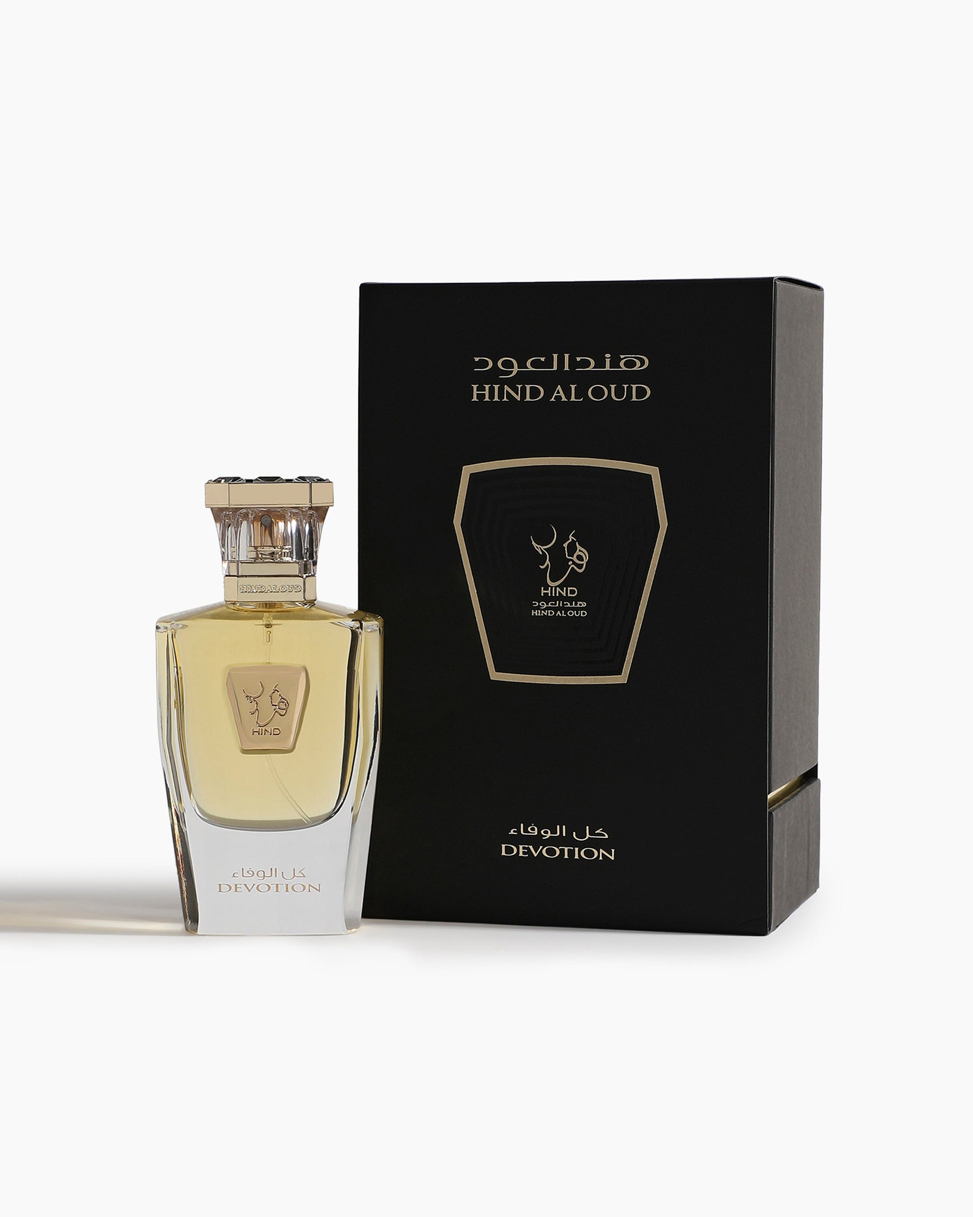 A bottle of Devotion Parfum by Hind Al Oud, an elegant oriental fragrance, sits beside its black and gold box—both featuring minimalist Arabic and English text.