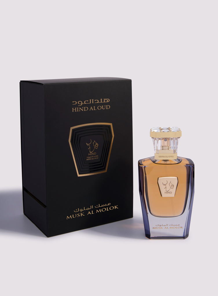 A bottle of Hind Al Oud's Musk Al Molok Parfum sits next to its sleek black and gold packaging, both adorned with Arabic and English text in a minimalist design, reflecting the luxury of this floral musk fragrance.