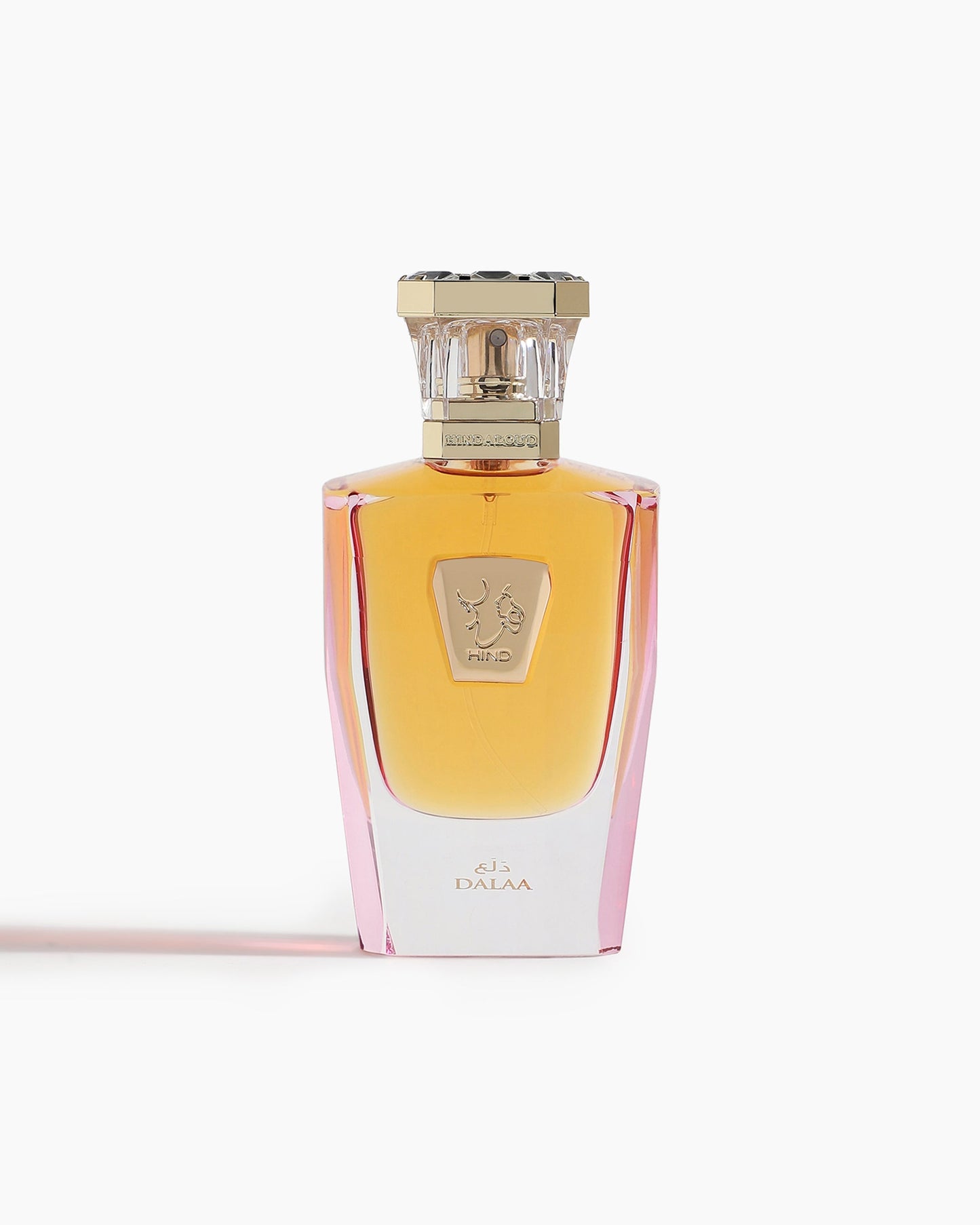 Dalaa Parfum by Hind Al Oud comes in a glass bottle with a gradient amber-pink hue, gold cap, and emblem label. “DALAA” appears at the base, reflecting the signature spicy floral scent of Hind Al Oud.