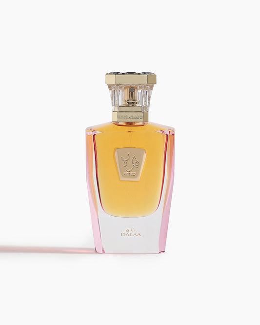 Dalaa Parfum by Hind Al Oud comes in a glass bottle with a gradient amber-pink hue, gold cap, and emblem label. “DALAA” appears at the base, reflecting the signature spicy floral scent of Hind Al Oud.
