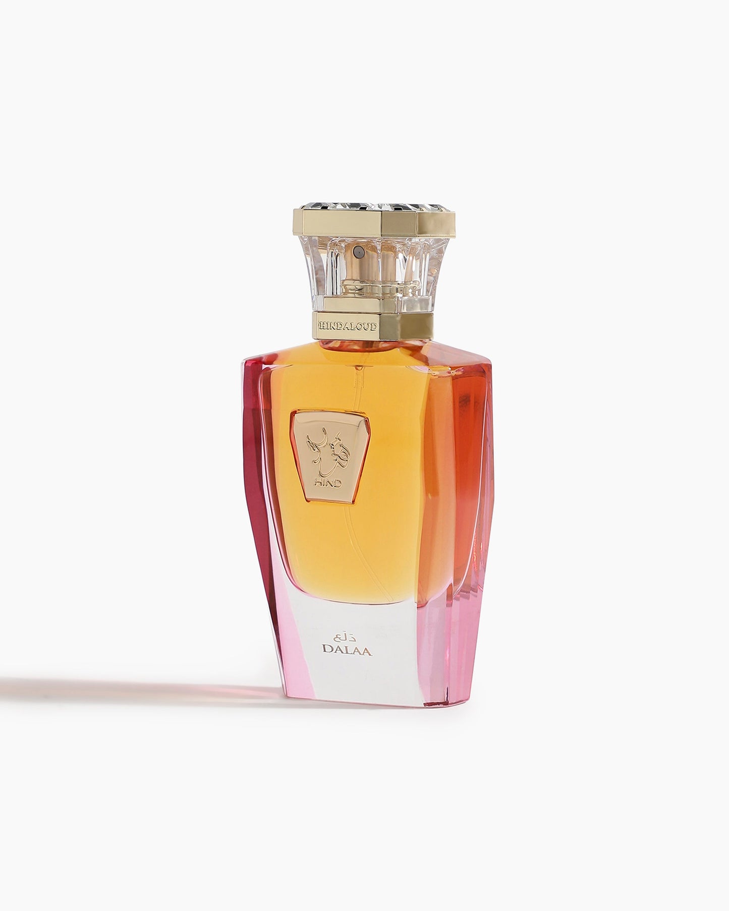 Dalaa Parfum by Hind Al Oud features a gold-capped bottle with an amber-to-pink gradient and a gold engraved label, set against a white background—an elegant vessel for its signature woody scent.