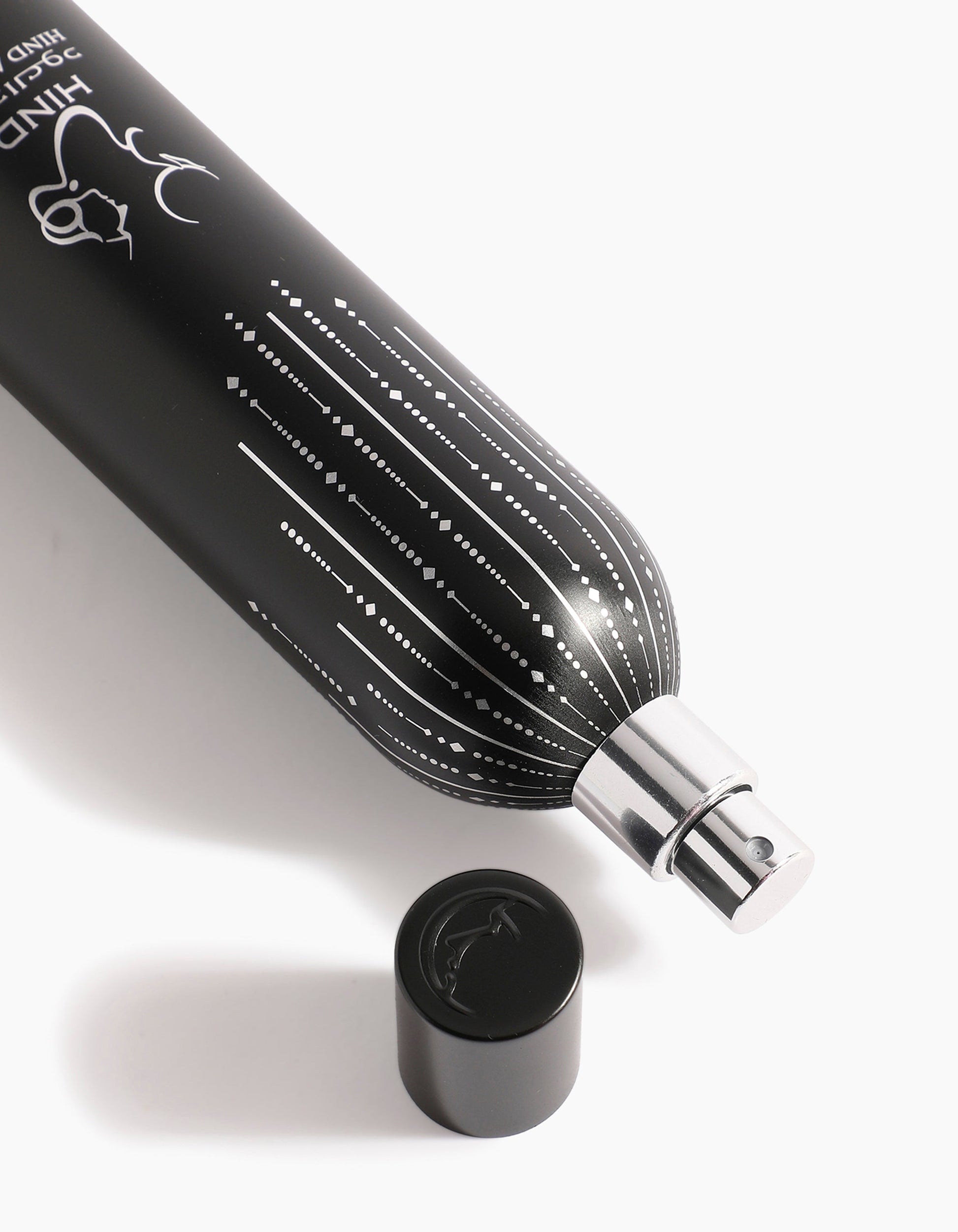A black Barari Body Spray bottle by Hind Al Oud with a silver nozzle and no cap rests on a white surface, displaying a white dotted line pattern and animal logo that evoke the rich essence of agarwood.