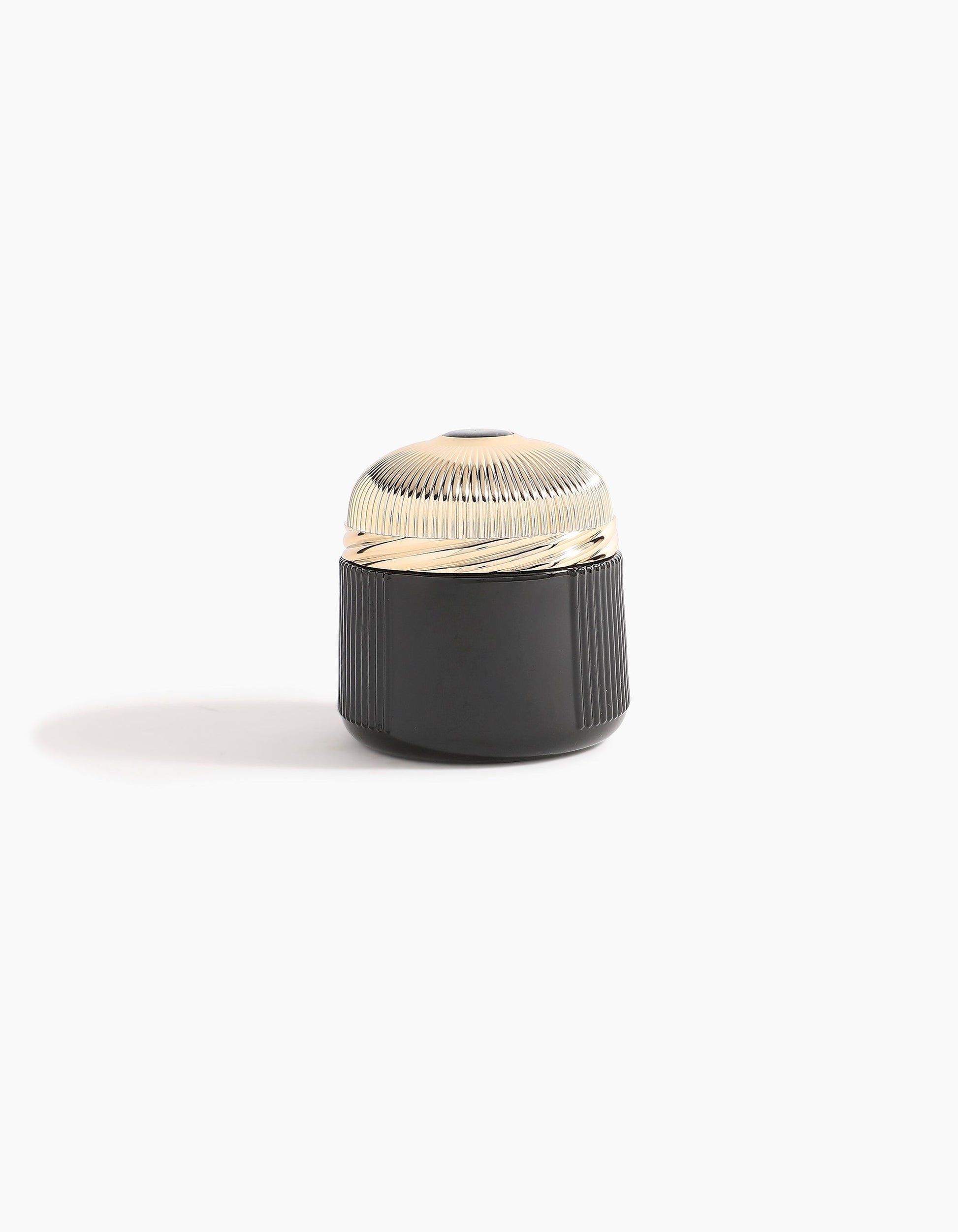 A small, round container with a ribbed, shiny gold lid and a black, textured base—echoing Agarwood luxury—Sheikh A Oud Mubakhar by Hind Al Oud rests on a plain white background with a soft shadow to the left.