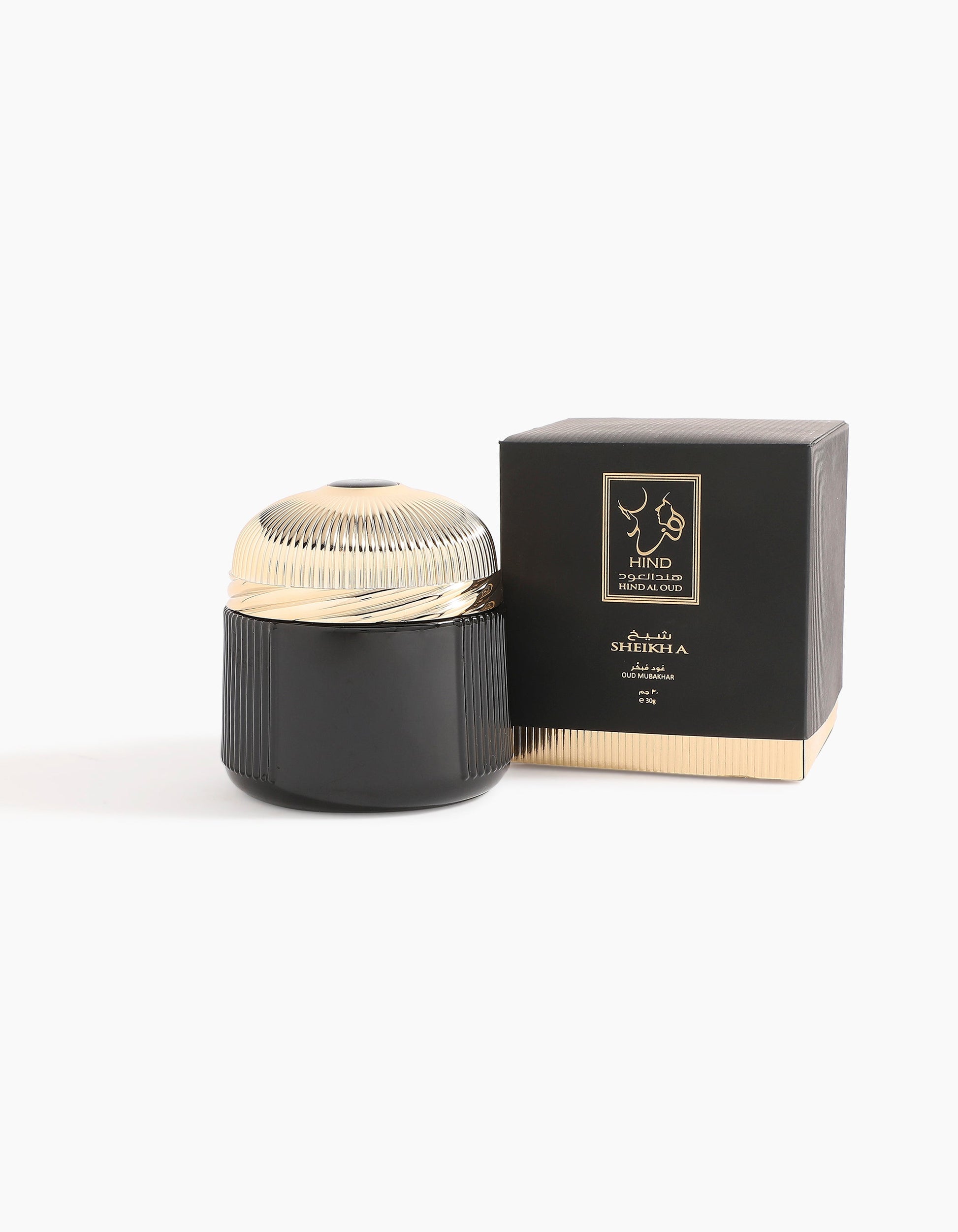 A black and gold ribbed jar with a gold lid, inspired by Hind Al Oud, sits beside a matching box labeled “Hind Al Oud” and “Sheikh A Oud Mubakhar.” Both appear against a plain white background.
