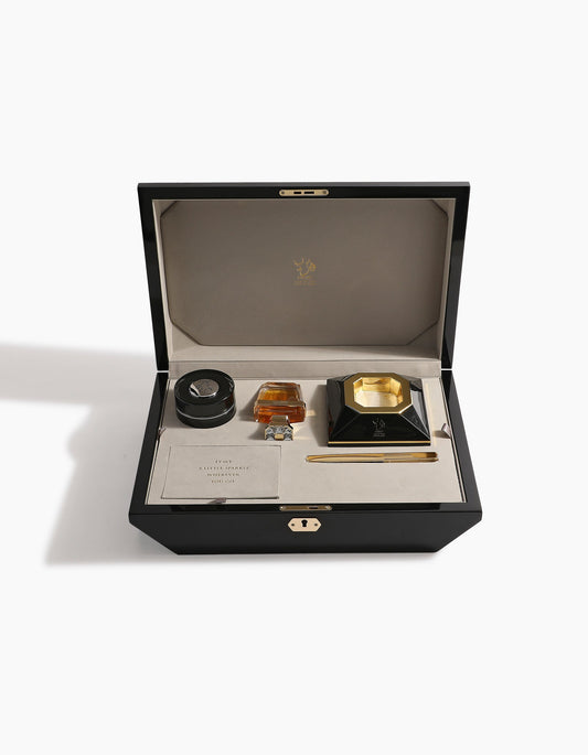 The Diamond Incense Kit Gift Box Option B by Hind Al Oud features a black luxury box with a beige interior, holding a round container, gold and black inkwell, pen, and card—perfectly arranged for an elegant presentation.