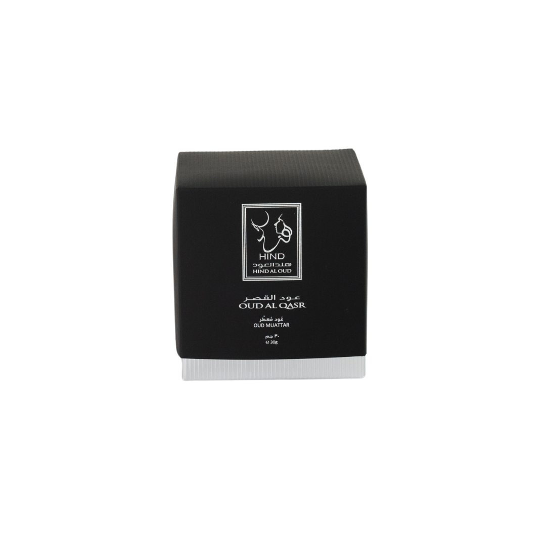 A black and gray square box labeled "Hind Al Oud" and "Oud Al Qasr Oud Muattar," with Arabic text, hints at a premium woody fragrance. The product is displayed on a plain white background. Brand: Hind Al Oud.