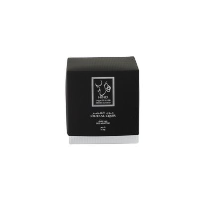 A black and gray square box labeled "Hind Al Oud" and "Oud Al Qasr Oud Muattar," with Arabic text, hints at a premium woody fragrance. The product is displayed on a plain white background. Brand: Hind Al Oud.