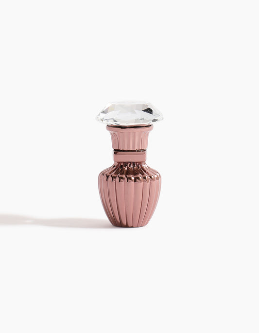 A small, metallic pink Seufi Qadeem Petite Concentrated Oil 3ml bottle by Hind Al Oud, featuring a ribbed design and a large, clear faceted lid, inspired by Emarati elegance and rich tradition, set against a white background.