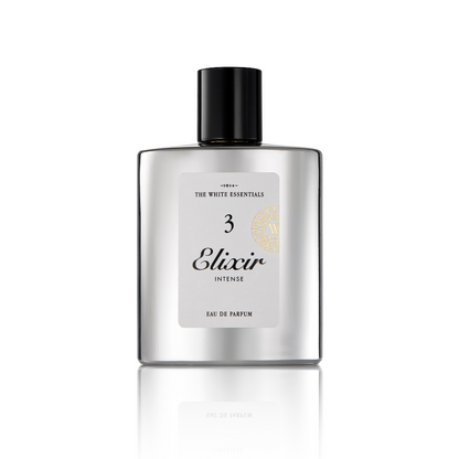 A silver rectangular bottle with a black cap, labeled Elixir 3 Intense Eau de Parfum by Jardin De Parfums, stands on a reflective white surface, evoking the essence of agarwood with elegant leather and cedar notes.