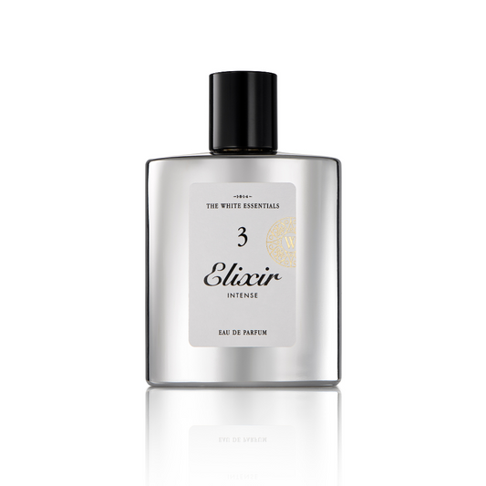 A silver rectangular bottle with a black cap, labeled Elixir 3 Intense Eau de Parfum by Jardin De Parfums, stands on a reflective white surface, evoking the essence of agarwood with elegant leather and cedar notes.