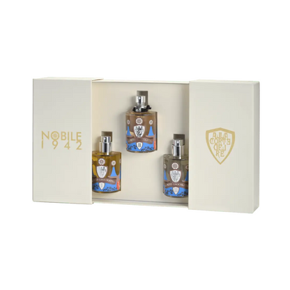 The cream-colored Le Petit Chocolatier - Nobile 1942 box set by Nobile 1942 features gold lettering and three detailed perfume bottles with silver caps, beautifully displayed in an open-sided box for this chocolate-inspired fragrance trio.