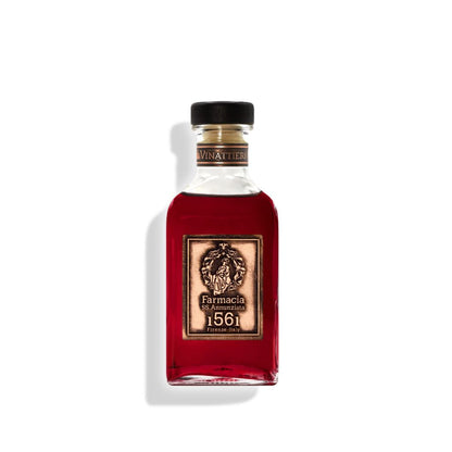 The Vinattieri DIFFUSER by Farmacia SS. Annunziata 1561 features a square glass bottle filled with dark red liquid, a black cap, gold Arte dei Vinattieri label with crest, and black sticks—hinting at a fruity wine fragrance diffuser.