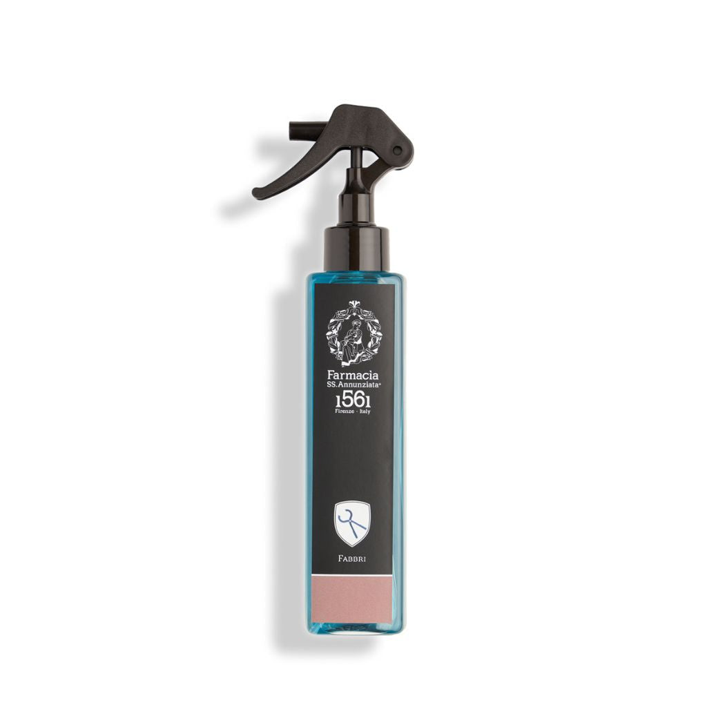 A rectangular blue Fabbri Room Spray bottle by Farmacia SS. Annunziata 1561 features a black trigger nozzle, white emblem, and a small scissors icon at the bottom.