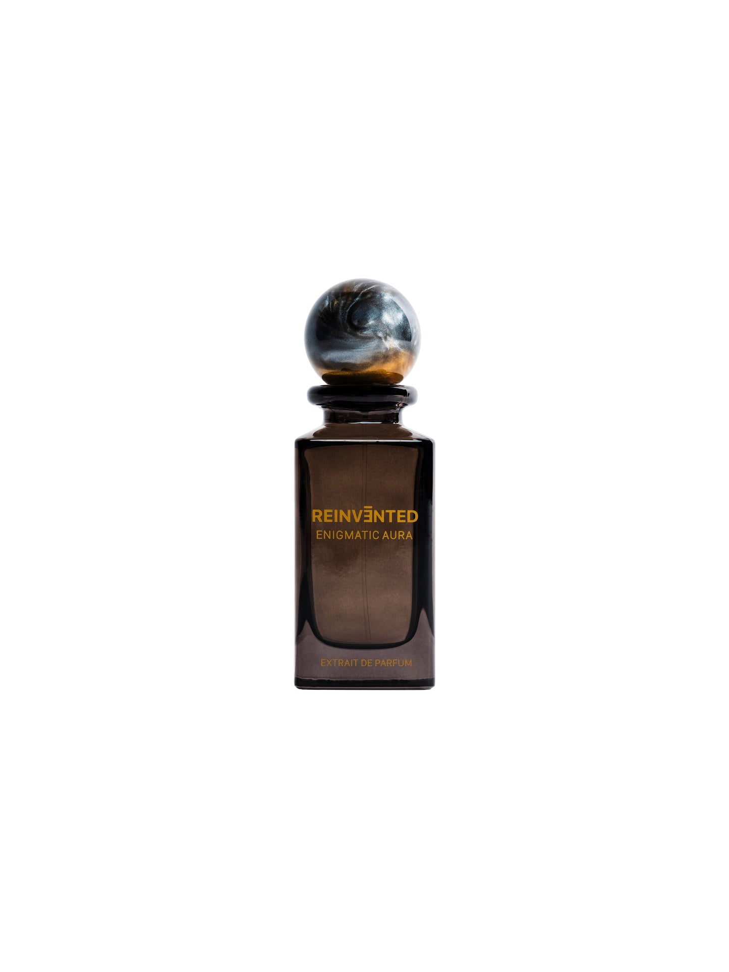 A dark brown glass bottle labeled ENIGMATIC AURA Extrait de Parfum - Reinvented by REINVĒNTED, with a round marble-like cap, is set against a white background—this vegan fragrance captures the mysterious essence of Enigmatic Aura.
