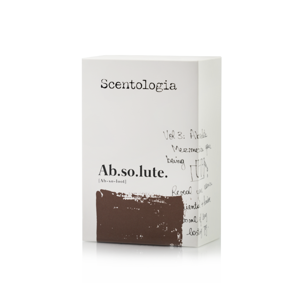 A white rectangular box labeled Scentologia features “Ab.so.lute. Eau de Parfum” in bold black text, handwritten notes and doodles on the side, and a brown brushstroke below that evokes sensual vanilla and amber musk.