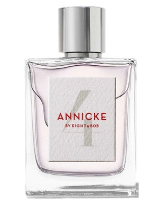 A clear glass bottle with a shiny silver cap, featuring a textured white label with Annicke 4 Eau de Parfum - Eight and Bob by Fragrapedia Haus. The light pink liquid inside suggests its floral fruity scent.
