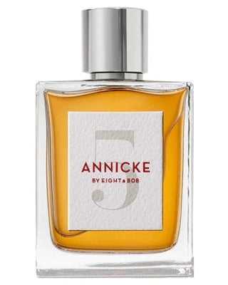 A rectangular glass bottle with amber perfume, a silver cap, and a white label reading Annicke 5 Eau de Parfum by Fragrapedia Haus, displays the allure of an Oriental Spicy scent in red and gray text.