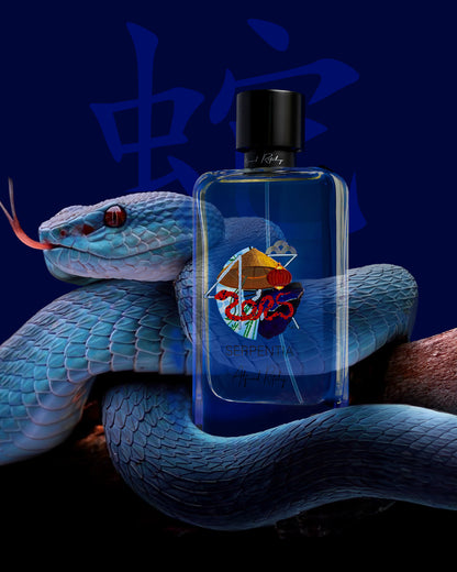 A sinuous blue snake wraps around a branch, tongue flicker sharp, as Alfred Ritchy’s SERPENTIA Eau de Parfum—its bottle adorned with vibrant art—stands before it. A subtle snake motif glows in the deep blue backdrop for Chinese New Year.