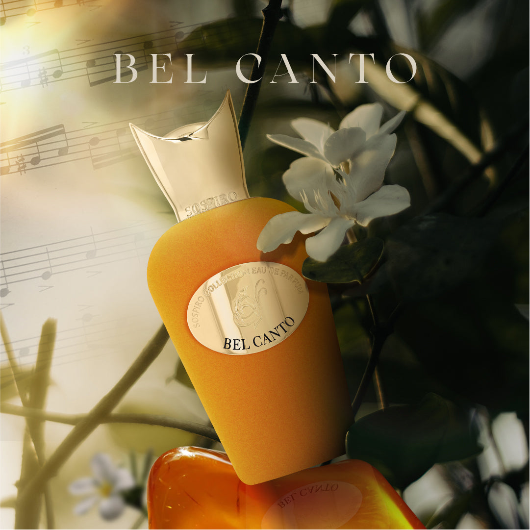 A gold-topped yellow bottle of Bel Canto Eau de Parfum by SOSPIRO rests among white blossoms and green leaves, with musical notes and "Bel Canto" text softly blurred in the background.