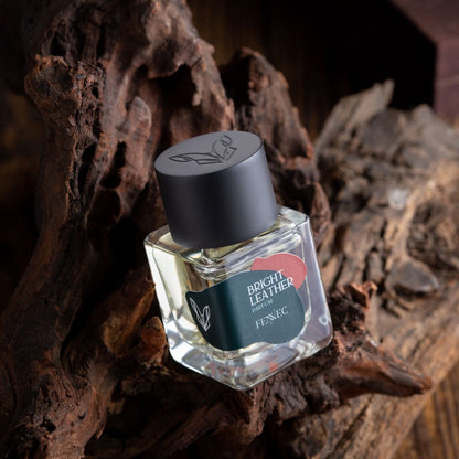 A glass Bright Leather Parfum bottle by Fennec rests on textured dark wood. It features a black cap, green label with a red heart, evoking North African spirit and the allure of the elusive fennec fox.