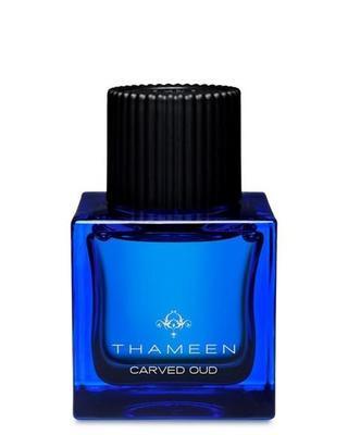 A square deep blue glass bottle with a black ribbed cap, labeled “CARVED OUD Extrait de Parfum - Thameen London” by Fragrapedia Haus—a temple-inspired scent featuring Indian Oud.