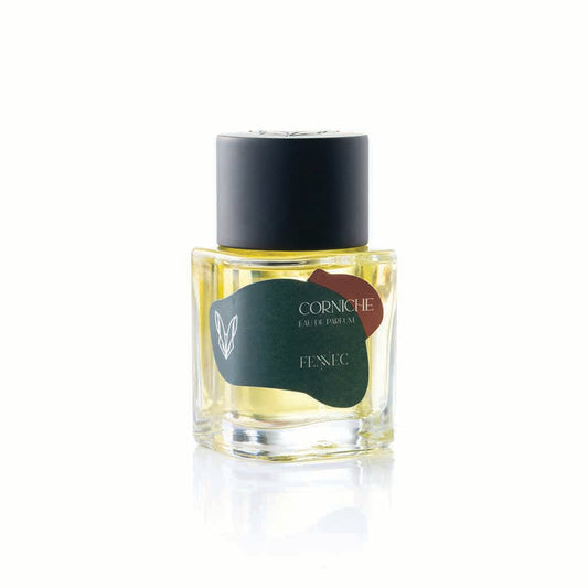 A clear glass bottle of Fennec Corniche EDP, featuring a black cap and dark green label, is displayed on a white background.