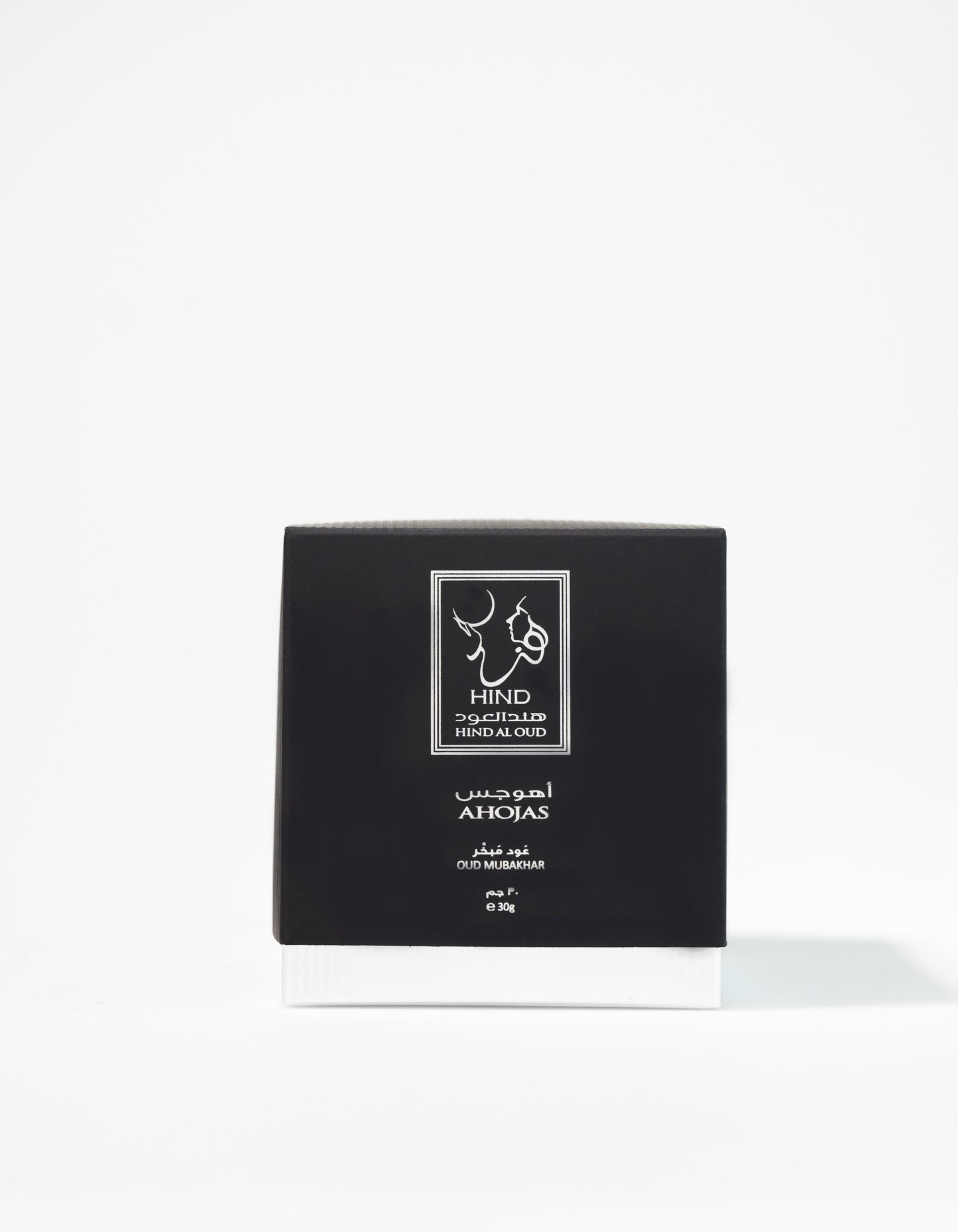 A black and white box labeled "Ahojas Oud Mubakhar - Hind Al Oud" by Hind Al Oud stands upright against a plain white background, evoking the rich allure of oud perfume.