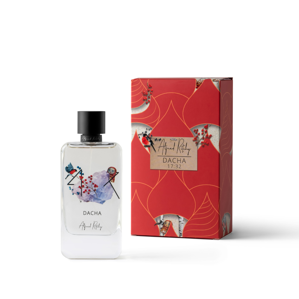 A clear 100ml perfume bottle labeled “DACHA Eau de Parfum - Alfred Ritchy” with abstract art and a black cap stands next to a red, gold, and white box featuring similar artwork and the “Alfred Ritchy” brand name.
