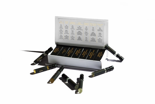 The Moseha Discovery Set features several 1.5 ml black vials with gold labels, arranged neatly in a white box. The lid displays a chart of the finest scents from Moseha. A few vials are scattered outside, all set against a plain white background.