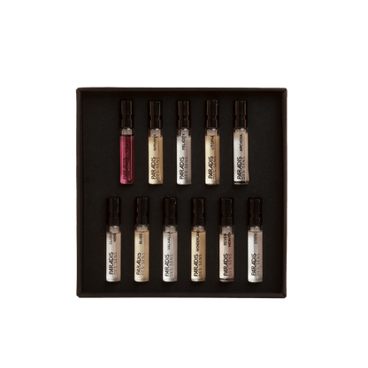 A black Discovery Set - Paradis Des Sens box by PARADIS DES SENS holds twelve labeled perfume samples in three rows on a light gray background—ideal for exploring and finding your next signature scent.