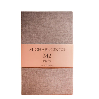 A rectangular box in textured beige with a peach band displays "M2 Eau de Parfum - Michael Cinco" by Fragrapedia Haus, 100 ml / 3.4 fl. oz., in elegant black font, reflecting a fragrance inspired by oriental spirituality.