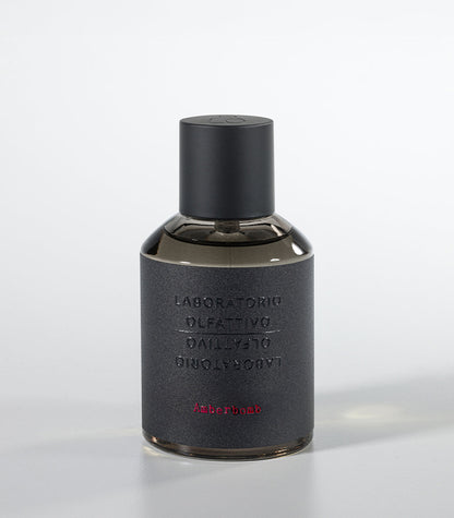 A dark, cylindrical Amberbomb Eau de Parfum bottle by Laboratorio Olfattivo features a matte black cap and textured gray label with silver brand text and red "Amberbomb," embodying the refined luxury of the Extreme Collection.
