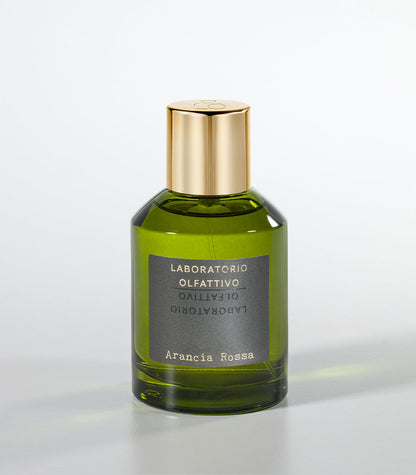 A green glass bottle of Laboratorio Olfattivo’s Arancia Rossa Eau de Parfum, featuring a gold cap and vibrant mandarin and bergamot notes, is set against a plain light gray background.
